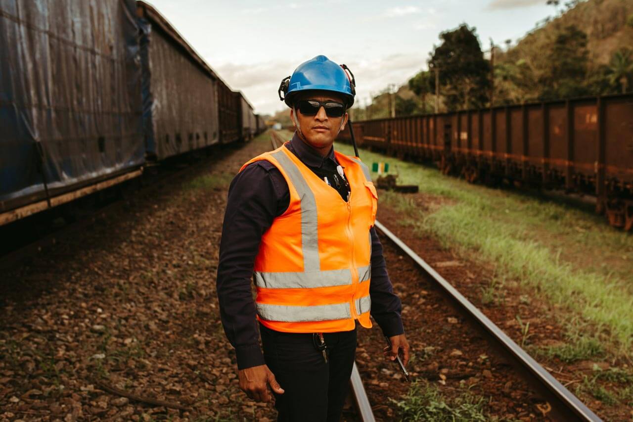 man with hard hat and reflective vest standing in front of railroad tracks