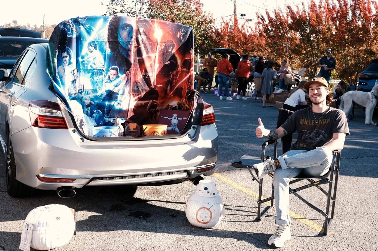 car with open truck and star wars blankets. man on right with a thumbs up
