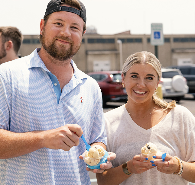 two people enjoying ice cream in a parking lot.