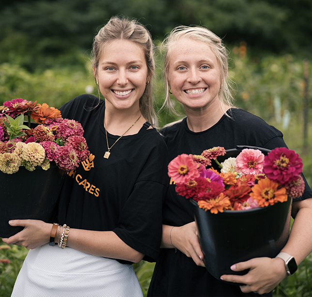 two women holding flowers in a garden