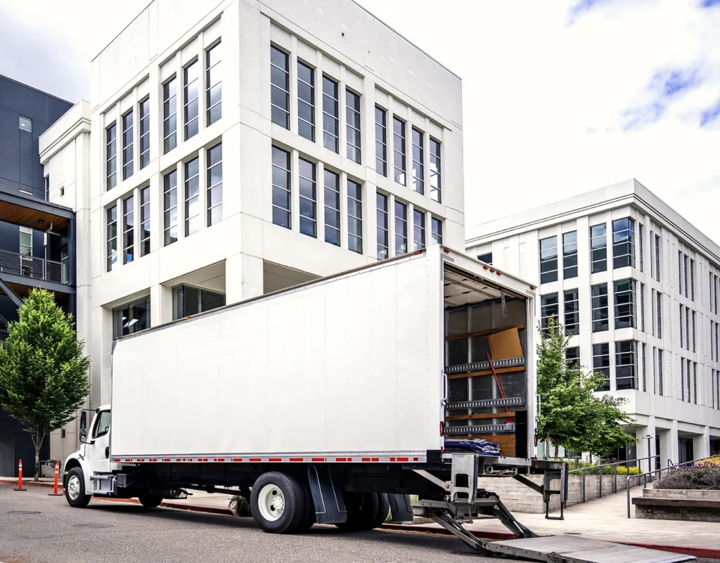 A truck unloads cargo in front of an office building.
